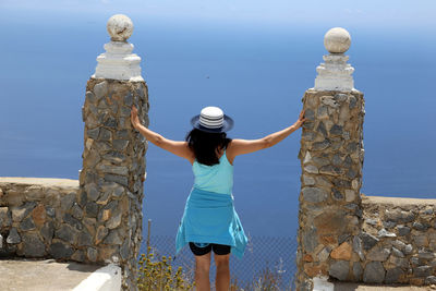 Rear view of woman standing by sea