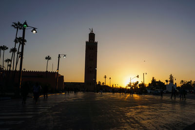 Silhouette of the koutoubia and people on the street against sky at sunset