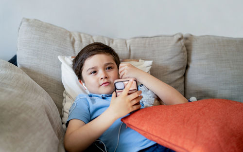 Portrait of happy boy relaxing on sofa at home