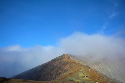 Scenic view of volcanic mountain against blue sky