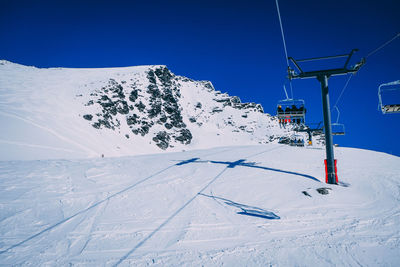 Ski lift over snow covered mountains against sky