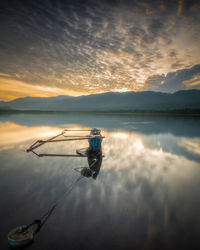 Reflection of man in lake against sky during sunset