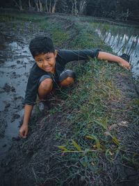 High angle portrait of boy crouching on grassy land