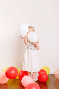 Cute girl standing with balloons at home