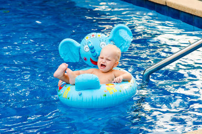 Baby boy on inflatable ring swimming in pool