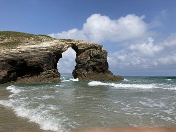 Rock formation on sea shore against sky