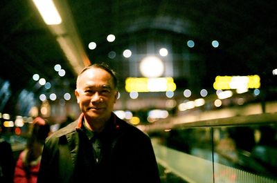 Portrait of young man standing in city at night