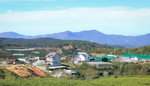 Houses on field by mountains against sky