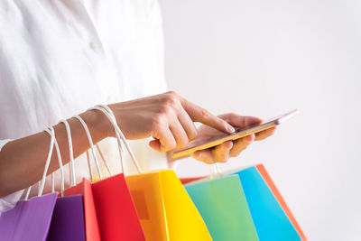 Midsection of woman using mobile phone against white background