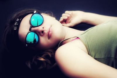 Close-up of teenage girl wearing sunglasses while lying outdoors