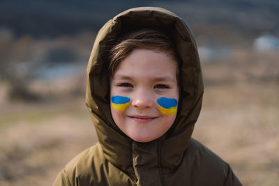 Portrait of a ukrainian boy with a face painted with the colors of the ukrainian flag.