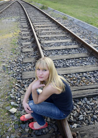 Young woman sitting on railroad track