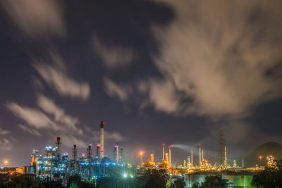 Illuminated oil refinery against sky at night