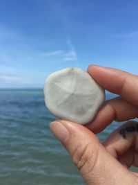 Close-up of hand holding sea against sky