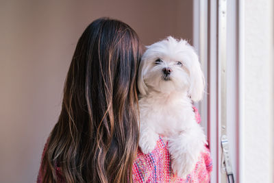 Rear view of woman with dog standing at home