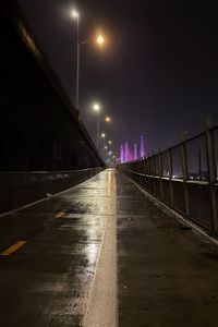 Illuminated bridge over road against sky at night