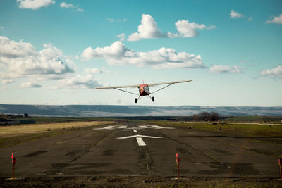 Airplane flying over road against sky