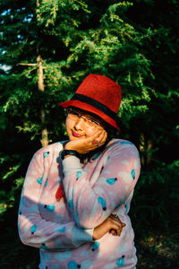 Portrait of young woman standing against plants