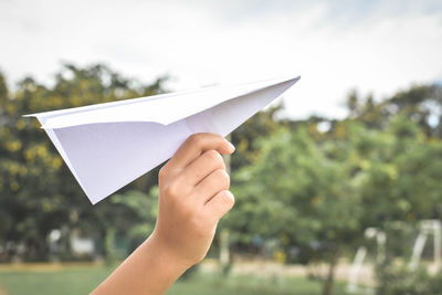 Close-up of hand holding paper airplane