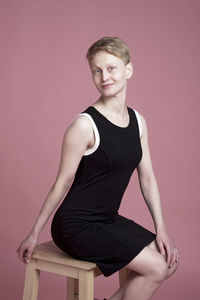 Portrait of man standing against pink background