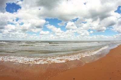 View of calm beach against cloudy sky