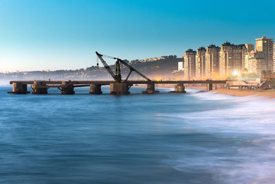 Bridge over sea against buildings in city