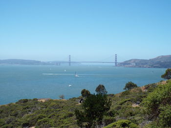 Suspension bridge over sea against clear sky