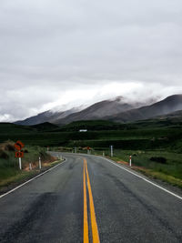 Road leading towards mountains against sky