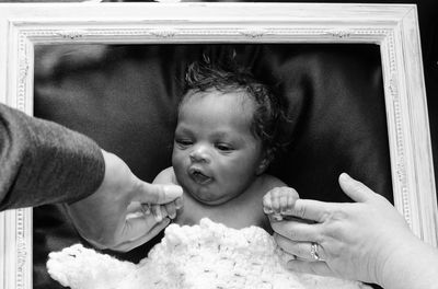 Cute baby girl holding cropped parents hands at home