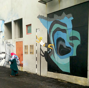 Rear view of woman walking on graffiti wall