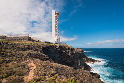 Lighthouse by sea against sky