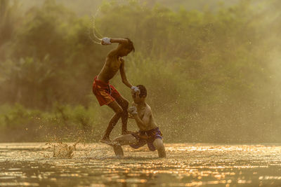 Shirtless boys playing in swamp