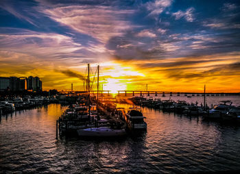 Sailboats moored on sea against sky during sunset