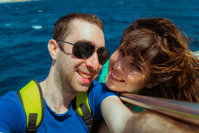 Close-up portrait of couple smiling against sea