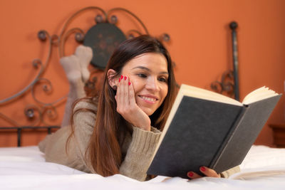 Portrait of young woman reading book on bed at home