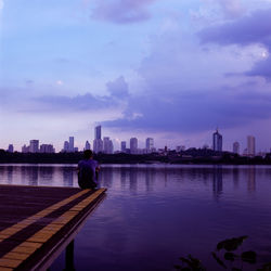 Man and buildings in city against sky