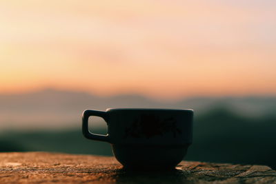 Close-up of coffee cup against orange sky