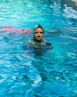Young girl wearing hijab and muslim swimming wear in the pool. happy active child.