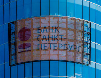 Low angle view of glass building against blue sky