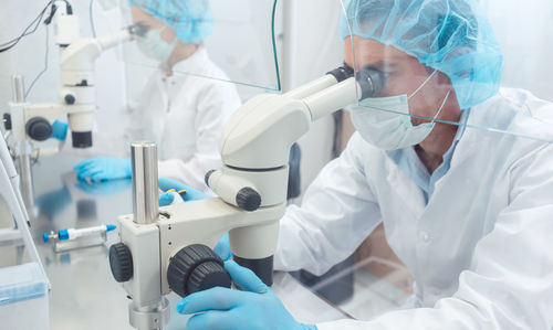 Close-up of man and woman looking at microscope at laboratory