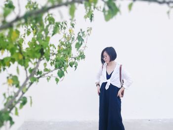 Woman looking away while standing against plants