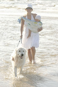 Portrait of woman with baby and dog standing on shore