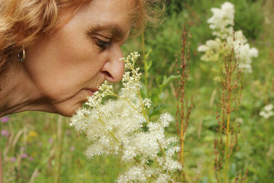 Close-up portrait of beautiful woman against white flowering plants