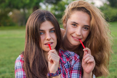 Portrait of young women eating candies on field