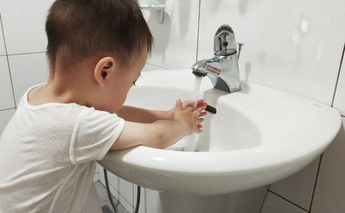 Side view of boy washing hands in bathroom