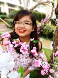 Portrait of smiling woman by pink flower