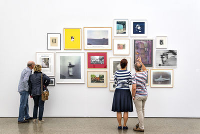 Rear view of woman photographing against wall in museum