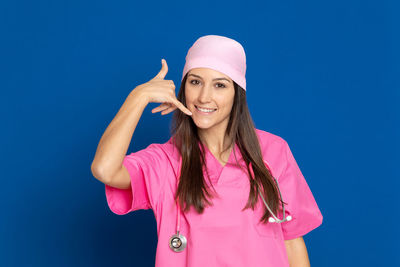 Portrait of smiling young woman standing against blue sky