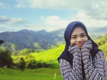 Portrait of smiling young woman wearing hijab with mountains in background