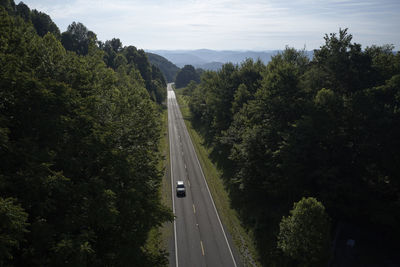 Road amidst trees in forest against sky